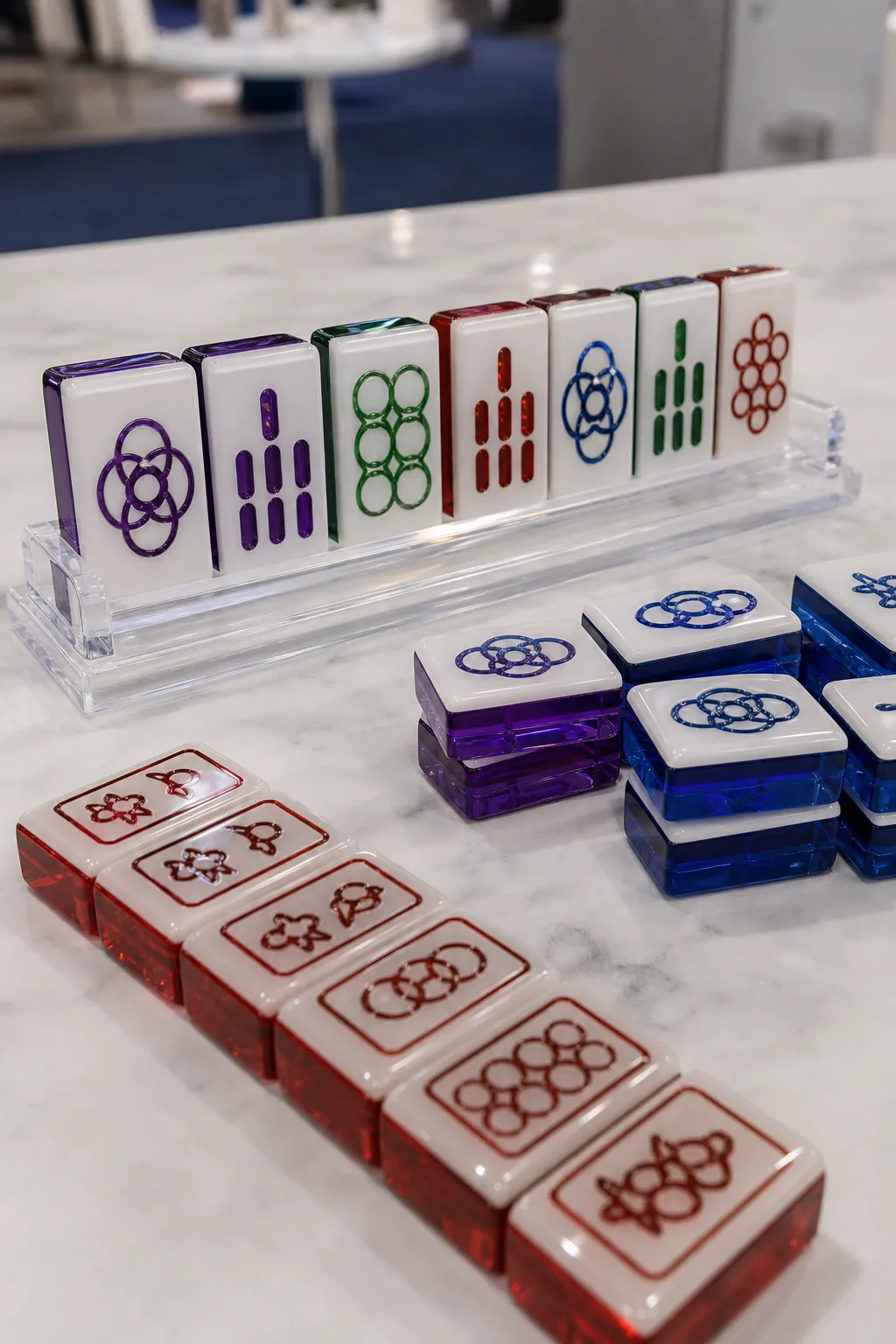 Custom acrylic American mahjong set with two-layer tiles — glossy cast PMMA faces over a pigmented back layer, engraved UV-filled characters — arranged on a trade-show booth table