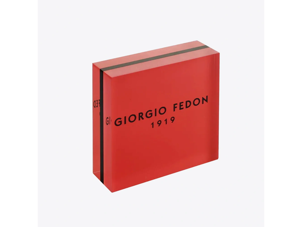 Solid red acrylic logo block with a printed black brand name