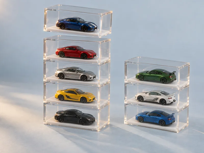 Two columns of stackable clear acrylic single-car cases, each holding one small die-cast car on a white base