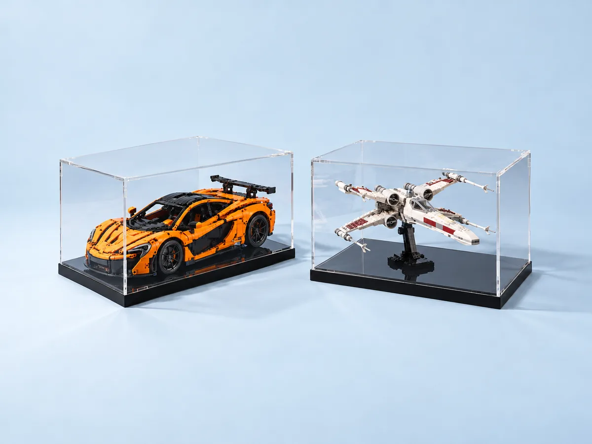 Brick model display cases in clear acrylic with black bases holding a built orange supercar and a built starfighter model