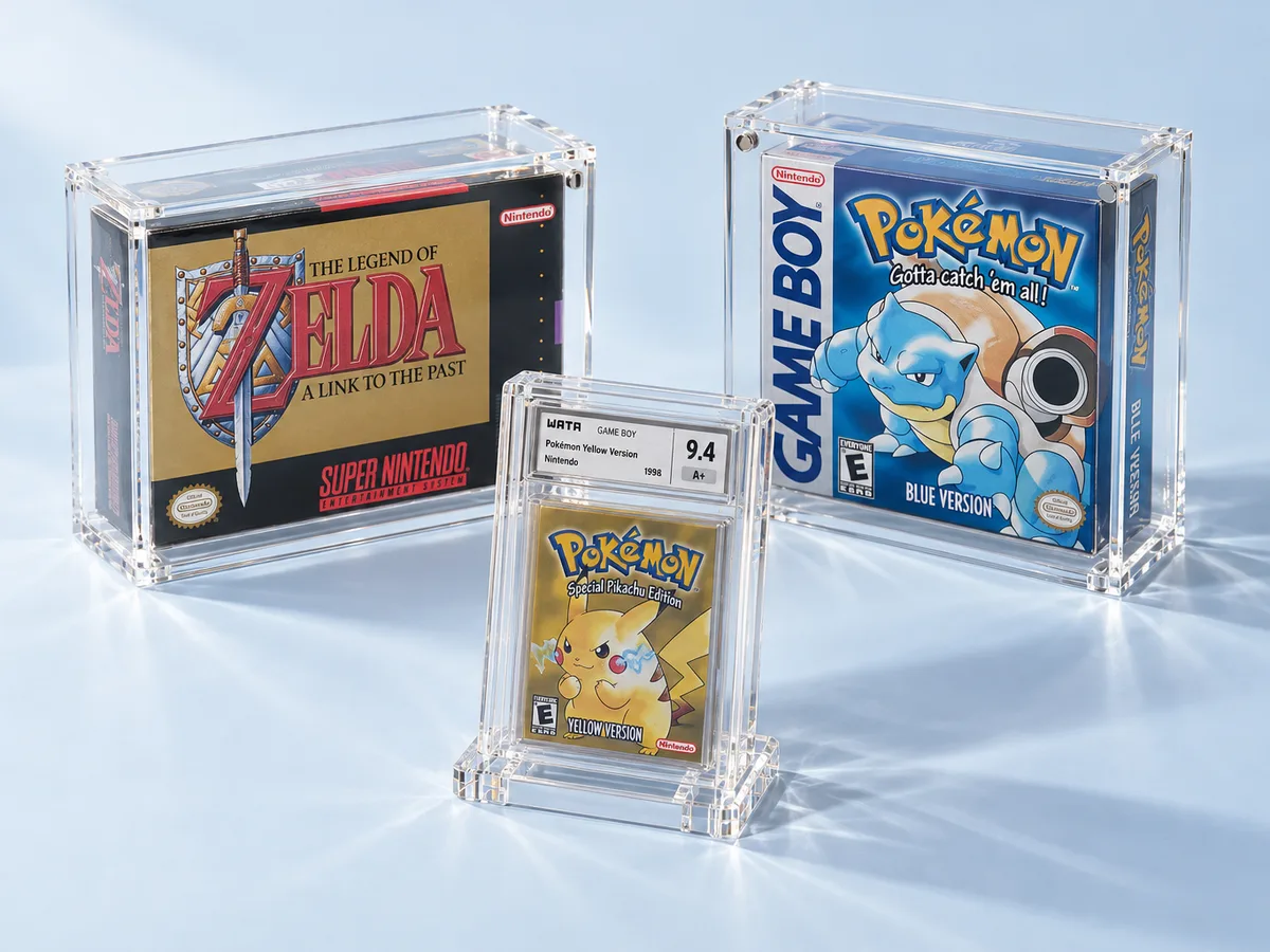 Video game display cases in clear acrylic holding two boxed retro games and a graded Pokemon game in a slab