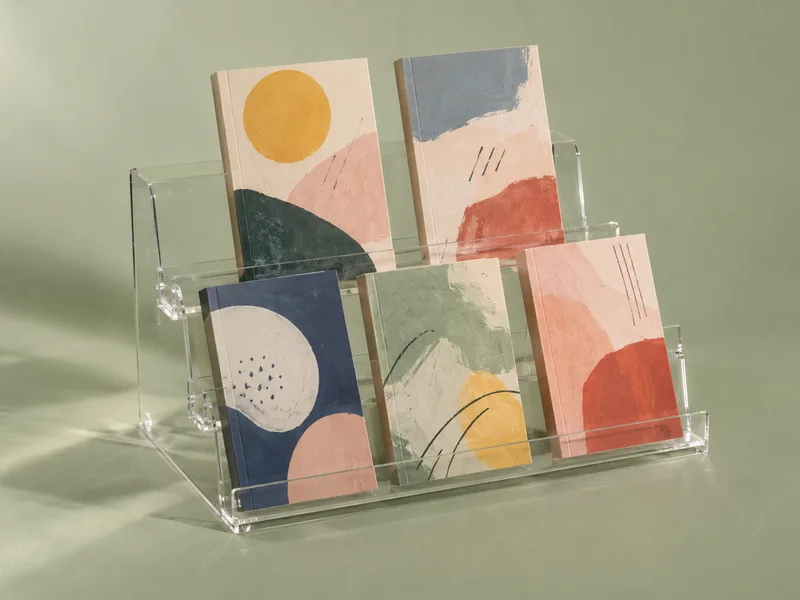 Two-step clear acrylic tiered book display stand holding five books face-out