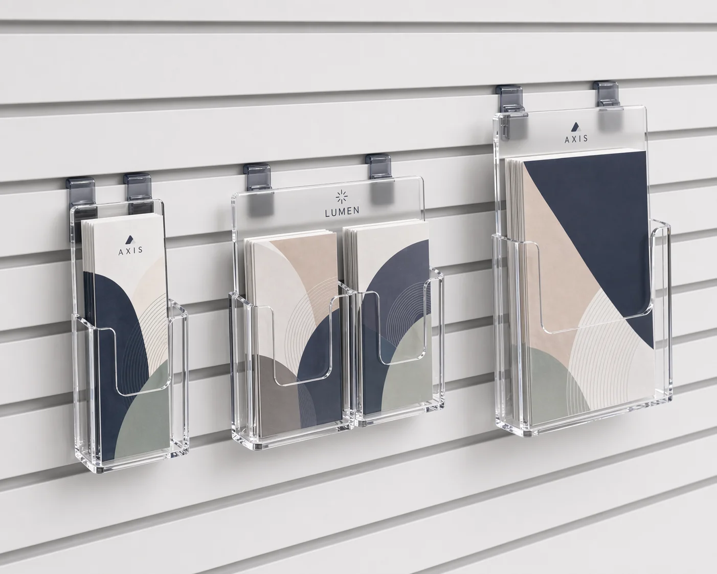 Slatwall-compatible acrylic brochure holders in single, double, and tall formats mounted on a retail slatwall panel