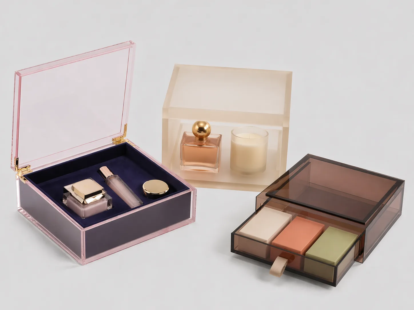 Three custom acrylic gift box styles on a clean light-gray background: hinged-lid cosmetics box, lift-off perfume box, and sliding drawer gift box